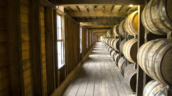 A long wooden walkway between racks of bourbon barrels in a Kentucky rickhouse.