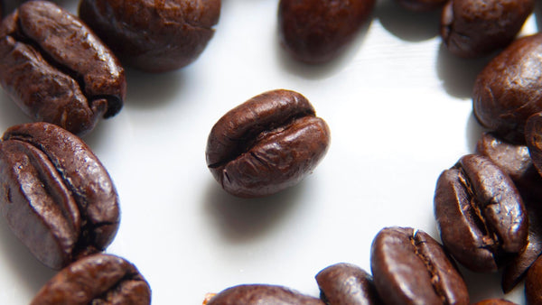 Macro photograph of glossy dark-roasted coffee beans.