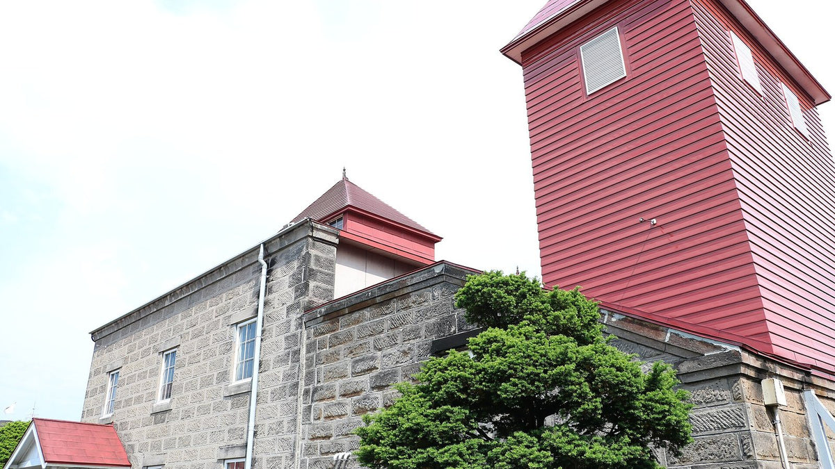 The red-clad still house tower and grey stone buildings of a Hokkaido whisky distillery.
