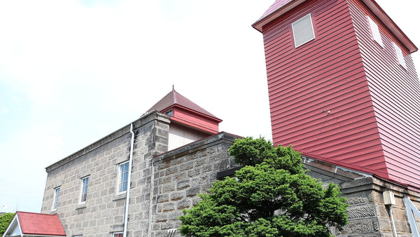 The red-clad still house tower and grey stone buildings of a Hokkaido whisky distillery.