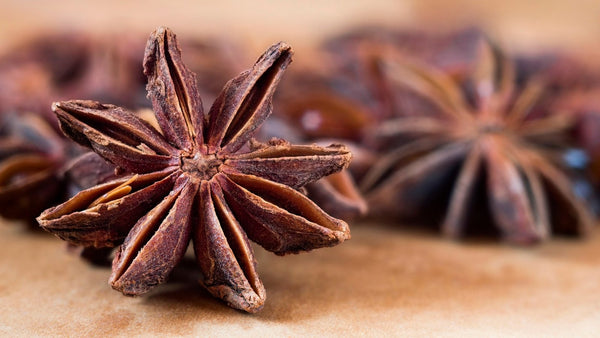 Close-up of whole star anise pods with seeds on a wooden surface.
