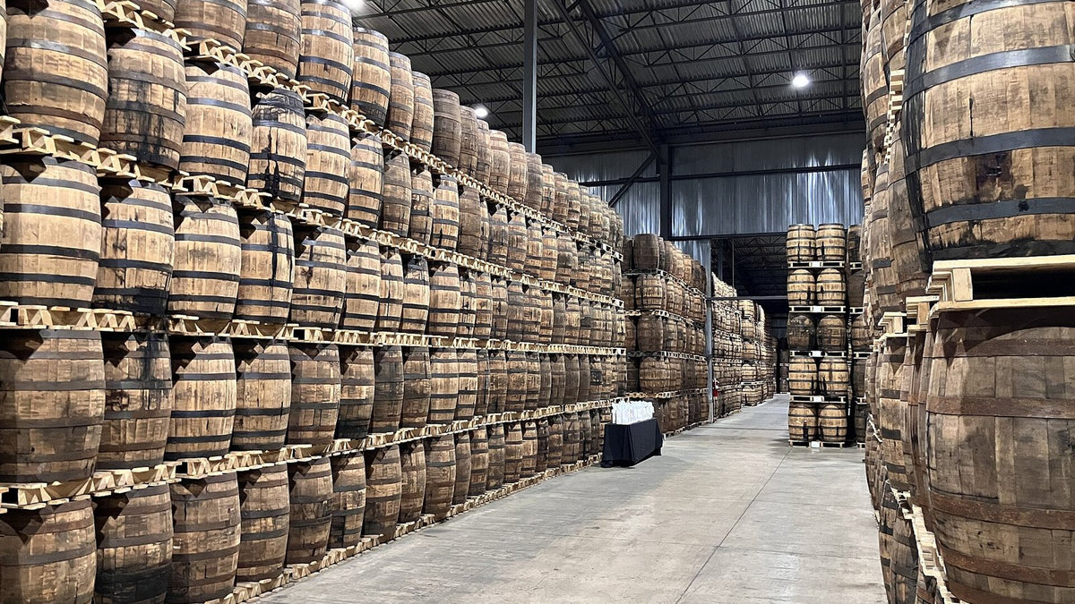 Tall stacks of palletised whisky barrels lining an aisle in an Ontario maturation warehouse.