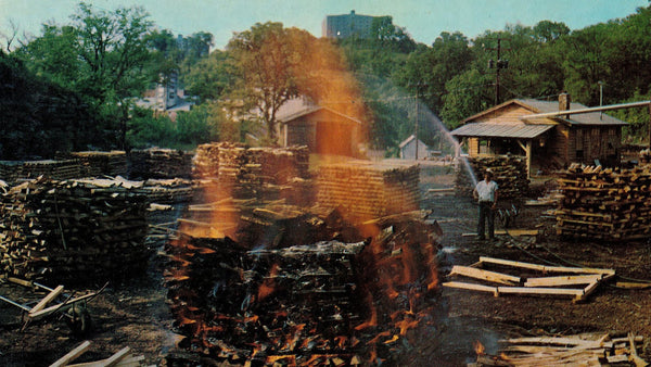 Stacks of sugar-maple wood burning in the open to make charcoal at a Lynchburg, Tennessee distillery.