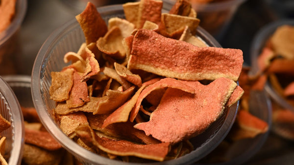 A bowl of curled, dried citrus peel in orange and brown tones.