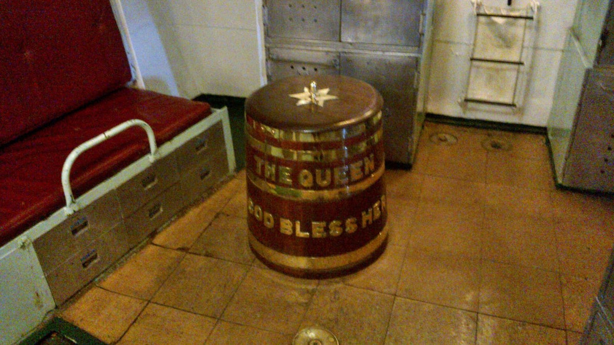 Brass-bound wooden grog tub lettered 'The Queen God Bless Her' aboard the museum ship HMS Cavalier.