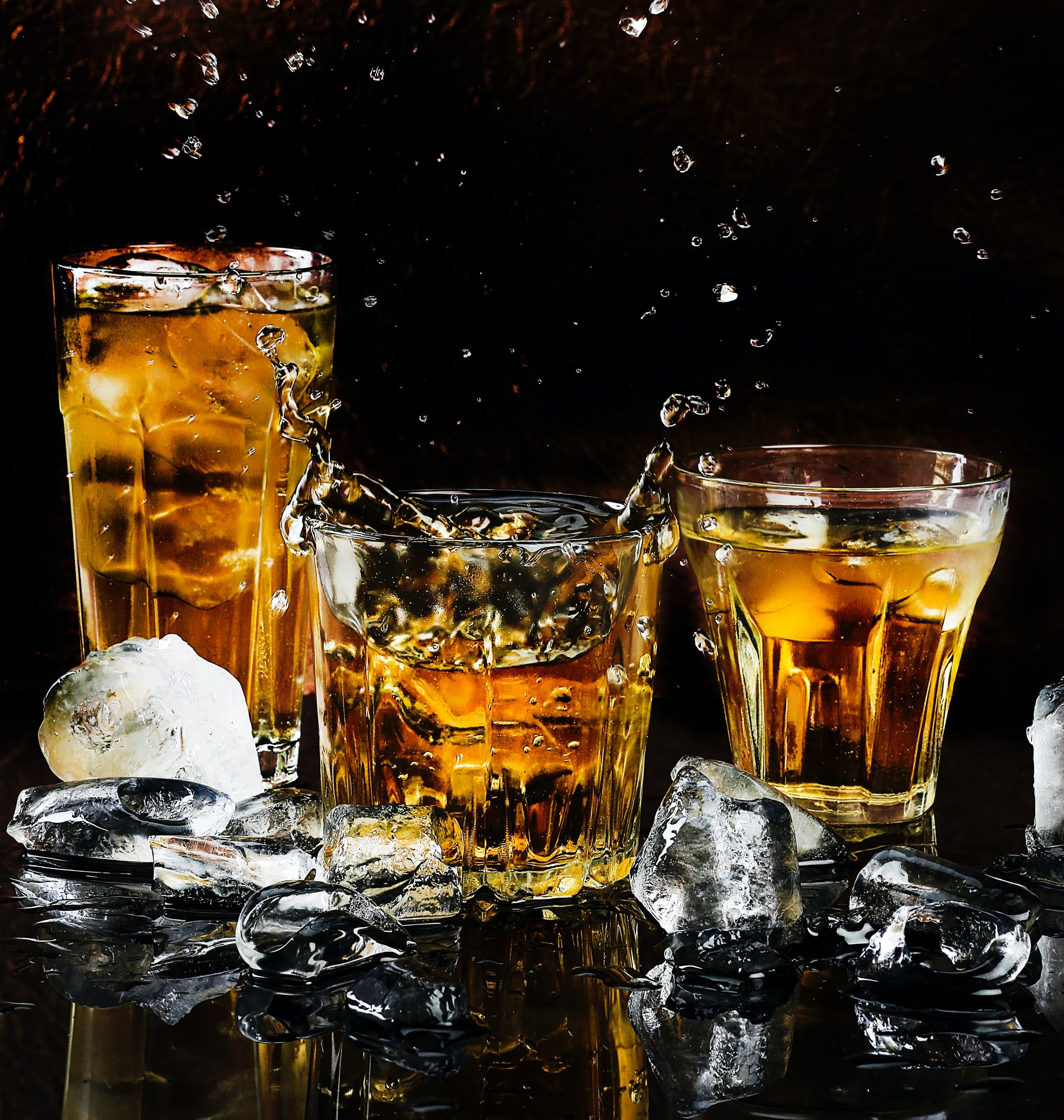 Three glasses of Straight Bourbon Whiskey with ice on a black background.